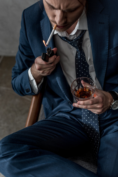 high angle view of businessman with glass of whiskey smoking cigarette - Foto, afbeelding