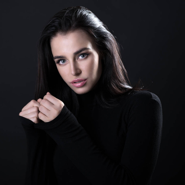 Beautiful girl posing over black background. Young pretty woman  - 写真・画像