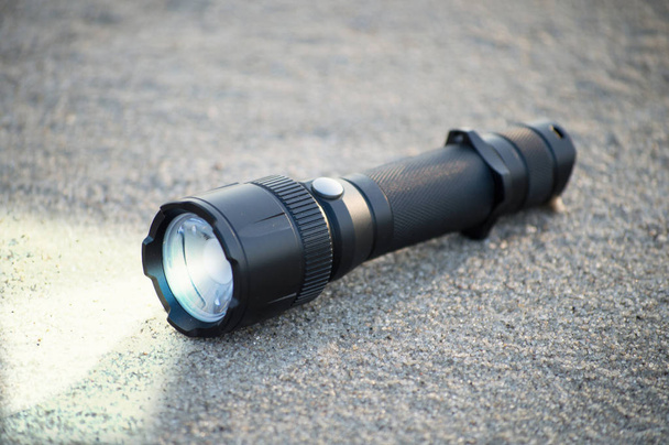 pocket LED flashlight lies on a sand - Foto, immagini