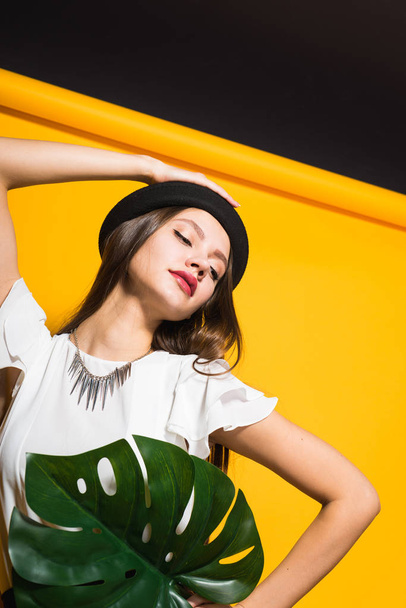 girl  in hat posing on yellow background - Foto, afbeelding