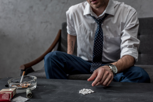 залежне джонкі в білій сорочці і краватці, приймаючи таблетки Мемми зі столу
 - Фото, зображення