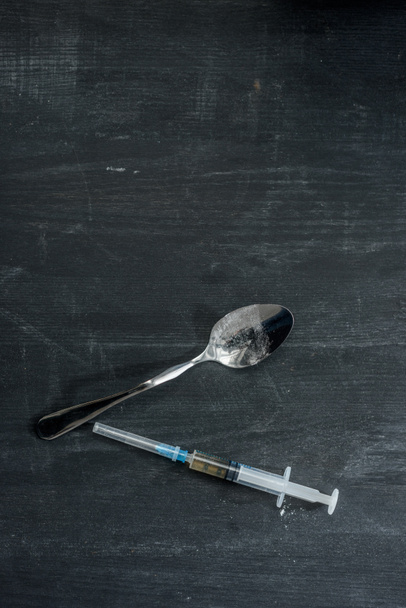 Ansicht von Heroinspritze und Kochlöffel auf Holzoberfläche - Foto, Bild