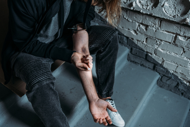 rajattu kuva heroiiniruiskeesta riippuvaisesta miehestä
 - Valokuva, kuva