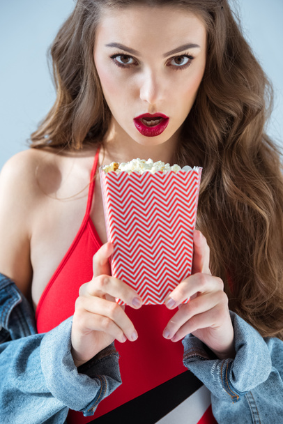 здивована сексуальна дівчина тримає попкорн і дивиться на камеру
 - Фото, зображення