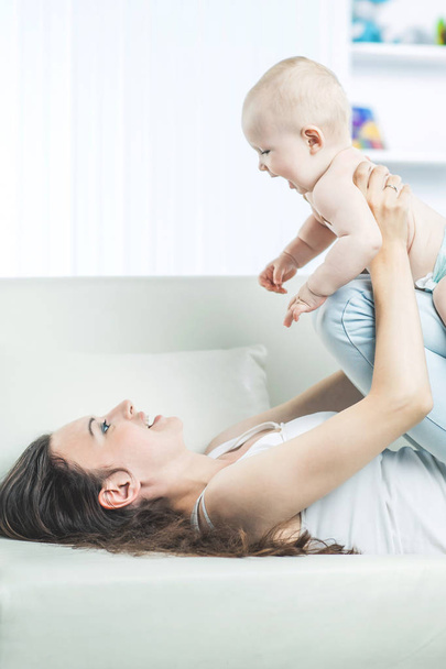 concept of motherhood:happy mother playing with one year old baby in the room for children - Fotoğraf, Görsel
