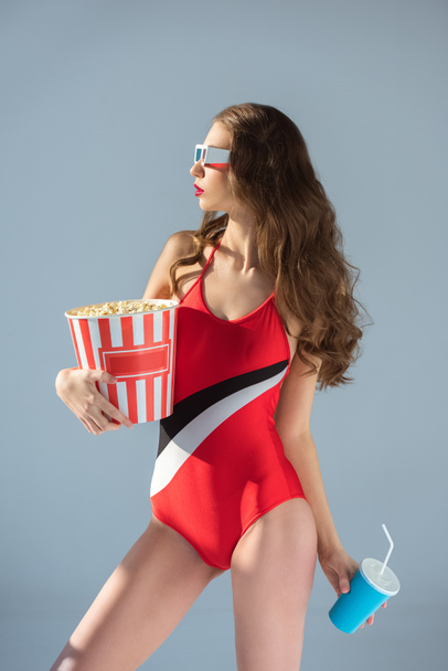 Widok z boku z uwodzicielski dziewczyna w strój kąpielowy i okulary 3d z popcornu na szarym tle - Zdjęcie, obraz