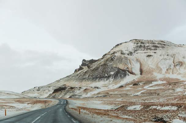 üres aszfaltozott út és a hóval borított festői hegyek, Izland   - Fotó, kép