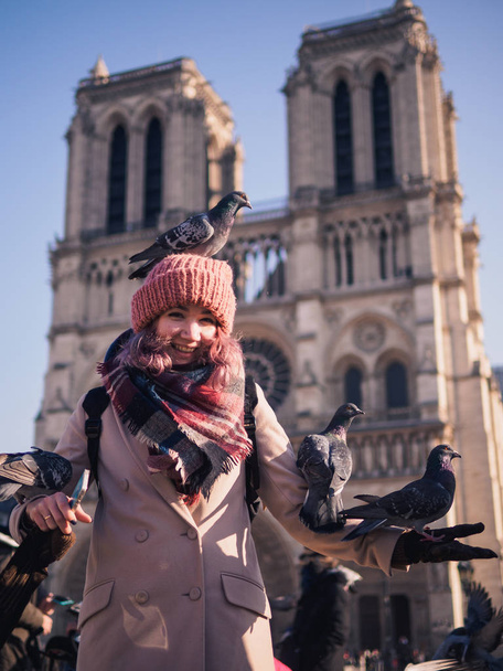 Girl feeding pigeons in the square in front of the cathedral of Notre Dame - Photo, Image