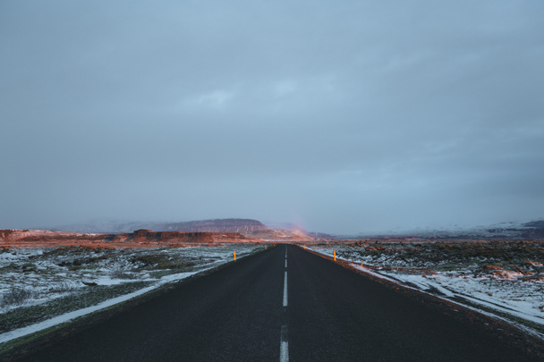 üres aszfaltozott út és a hóval borított Izlandi táj napkeltekor - Fotó, kép