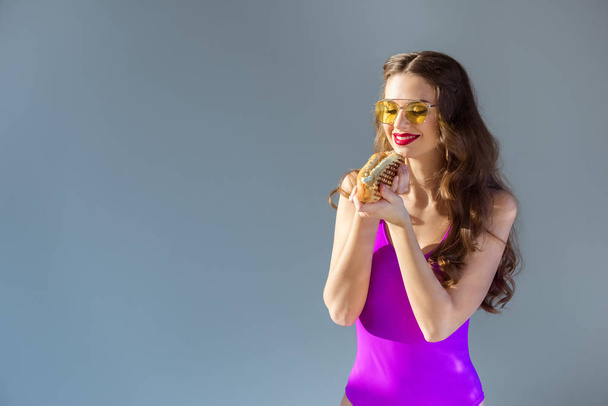 sexy smiling girl in ultra violet swimsuit holding hot dog isolated on grey - Foto, afbeelding