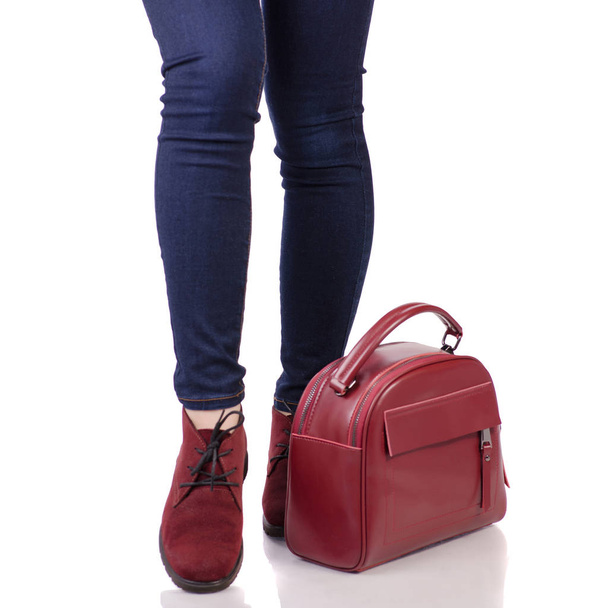 Pernas femininas em jeans e em sapatos de camurça vermelha com bolsa de couro vermelho
 - Foto, Imagem