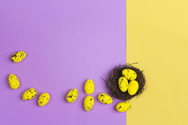 Small yellow eggs in a nest on yellow and violet background. Cop - Foto, Bild