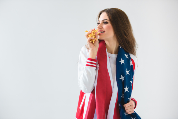 sexy dziewczyna uśmiechający się flagą usa jedzenia frytek na białym tle - Zdjęcie, obraz