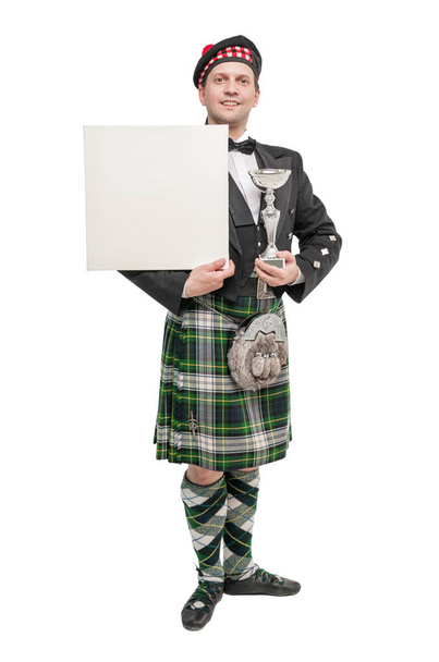 Молодой человек в одежде для шотландских танцев с пустым баннером
  - Фото, изображение
