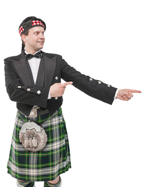 Όμορφος άνδρας στο παραδοσιακό σκωτσέζικο κοστούμι επισημαίνοντας σχετικά με somethi - Φωτογραφία, εικόνα