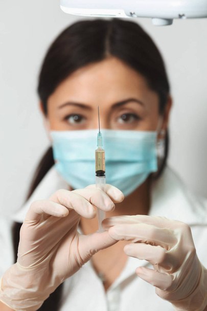 The cosmetician holds a syringe with a preparation - Fotoğraf, Görsel