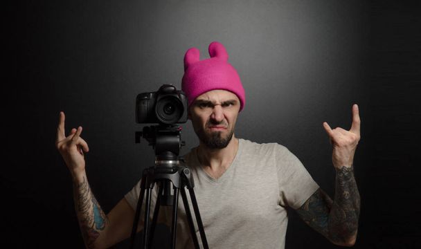 Ein Mann mit Stativ und Videokamera drückt Emotionen aus - Foto, Bild