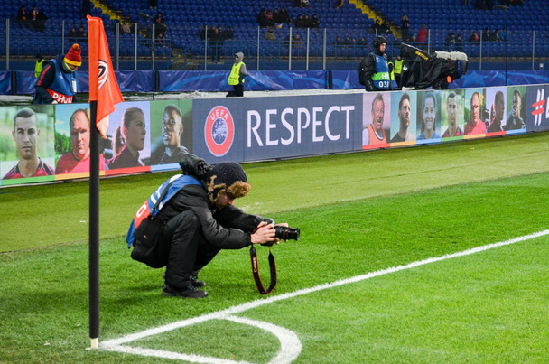 KHARKIV, UKRAINE - FEBRUARY 21, 2018: Photographer makes a frame sitting on the lawn during UEFA Champions League match between Shakhtar Donetsk vs AS Roma, Ukraine - 写真・画像