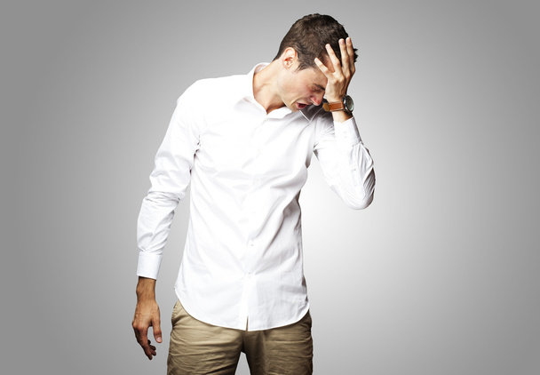 Angry young man doing frustration gesture over grey background - Photo, Image