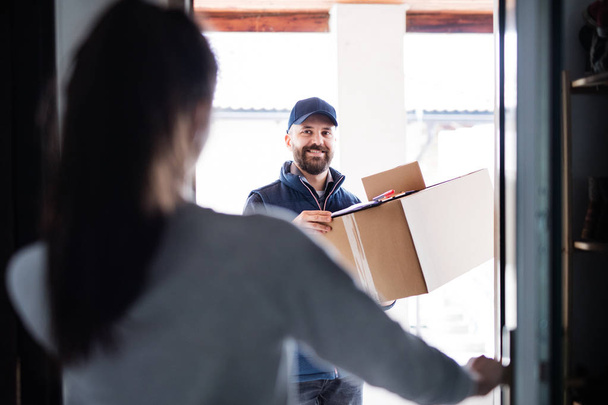 Woman receiving parcel from delivery man at the door. - Foto, immagini