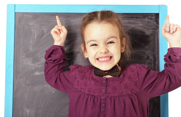 Schattig liitle meisje permanent in de buurt van blackboard en gelukkig lachend. BEA - Foto, afbeelding