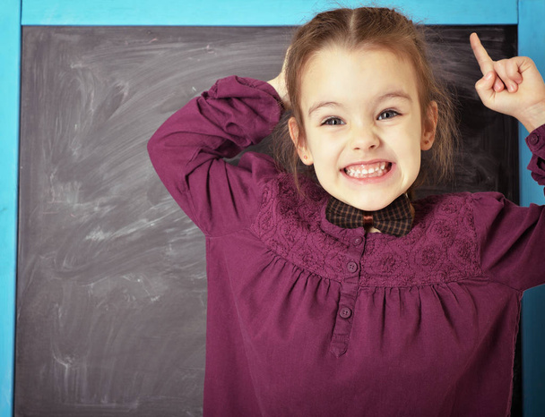 Cute liitle emotional girl standing near blackboard and happy sm - Photo, Image