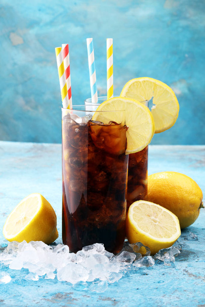 Softdrank met ijsblokjes, citroen en stro in glas. - Foto, afbeelding