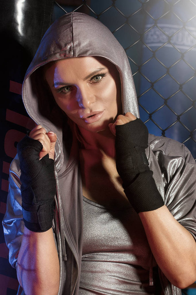 Female boxer posing inside a boxing cage. - Фото, изображение