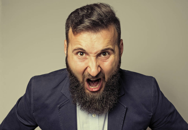 Понятие гнева. Портрет кричащего бородатого человека в деловом костюме
. - Фото, изображение