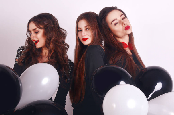 Crazy party time of three beautiful stylish women in elegant evening casual black dress celebrating , having fun, dancing on white background. Best friends girls with black and white balloon . - Photo, Image