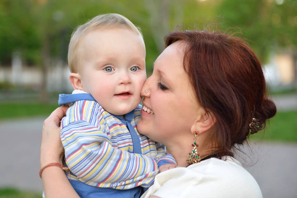 Happy mother holding her adorable little son. Family outdoor lei - Photo, Image