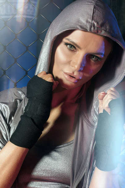 Female boxer posing inside a boxing cage. - Foto, Imagen