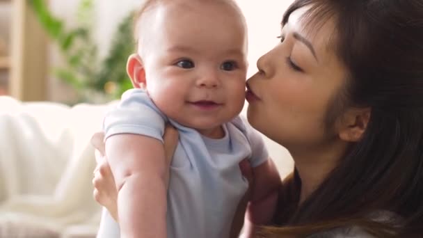 feliz joven madre besando poco bebé en casa
 - Imágenes, Vídeo