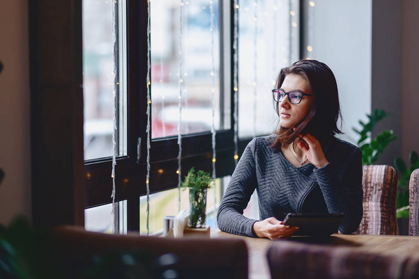 Una chica guapa con gafas trabaja en una mesa de café
 - Foto, imagen