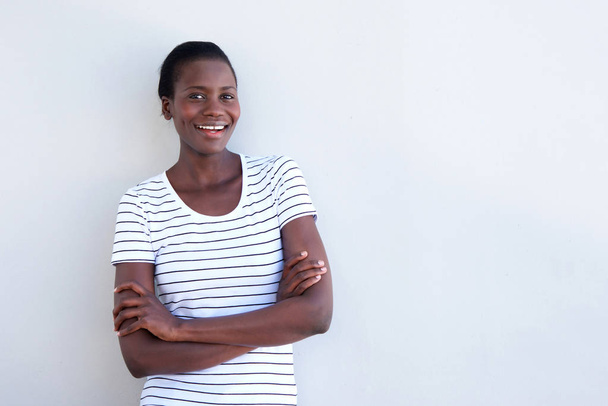Retrato de mulher afro-americana sorrindo com os braços cruzados sobre fundo branco
 - Foto, Imagem