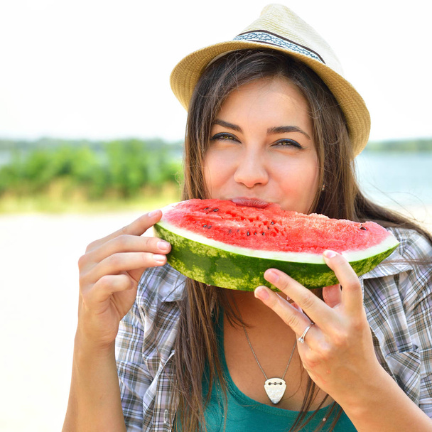 Happy young woman eating watermelon on the beach. Youth lifestyl - 写真・画像