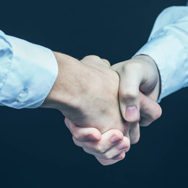 concept of a reliable partnership: a close-up of handshake of business partners on a black background. - Foto, immagini