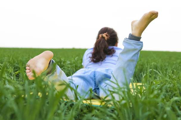 woman lying in fresh green grass. summer time season. unrecognizable person - Photo, Image