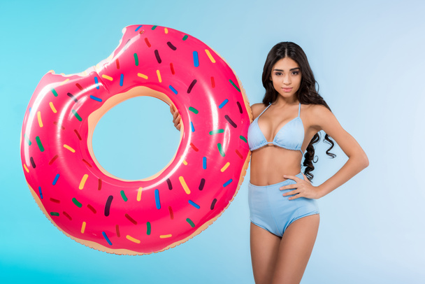 attractive girl posing with inflatable donut ring, isolated on blue  - Foto, Imagen