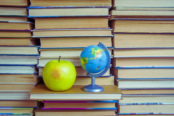  globe, green apple  against books texture. back to school idea - Foto, immagini