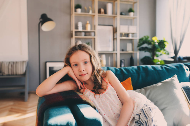 cute kid girl relaxing at home in cozy weekend morning in sunny living room with modern scandinavian interior - 写真・画像