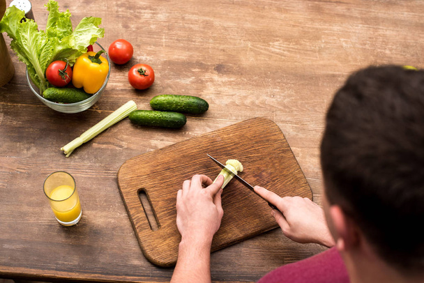 selective focus of man cutting celery on wooden chopping board  - Fotoğraf, Görsel