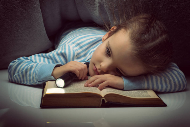 Kleines Mädchen liest am Vorabend unter dem Cover ein Märchenbuch - Foto, Bild