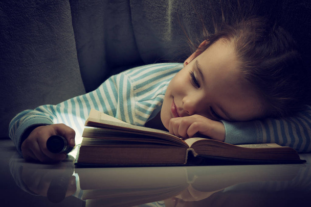 Μικρό κορίτσι ανάγνωση παραμυθιών βιβλίο κάτω από τα σκεπάσματα την παραμονή - Φωτογραφία, εικόνα