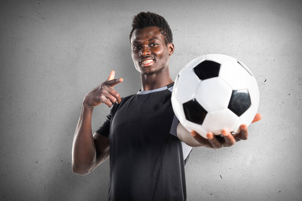 Hombre negro jugando fútbol sobre fondo texturizado
 - Foto, imagen