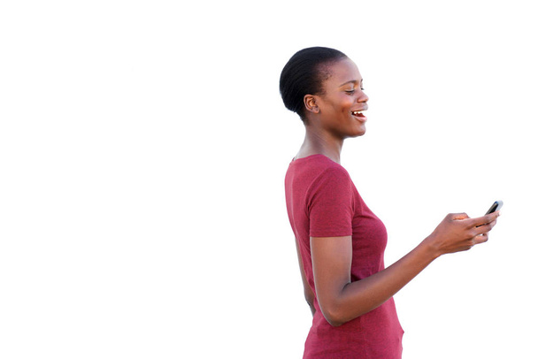 Po stronie portret szczęśliwy młoda kobieta, patrząc na telefon komórkowy i śmiejąc się na białym tle - Zdjęcie, obraz