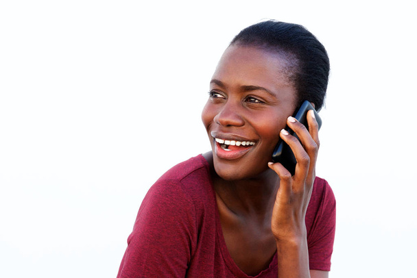 Portrait of young african woman making phone call looking over shoulder and smiling on white background - Photo, Image