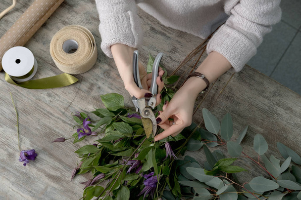 The hands of florist against desktop with working tools and ribb - Φωτογραφία, εικόνα