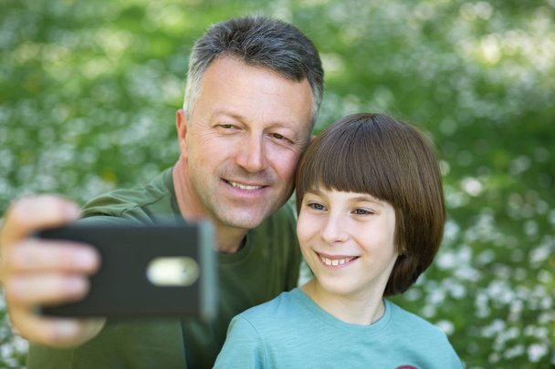 Father and son taking photo with smartphone together outdoor. Fa - Фото, зображення