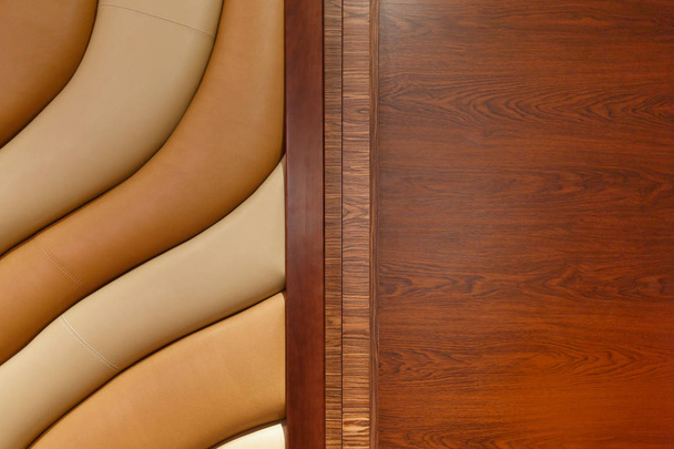Leather, stitched, wavy texture and a brown wood door. - Photo, Image